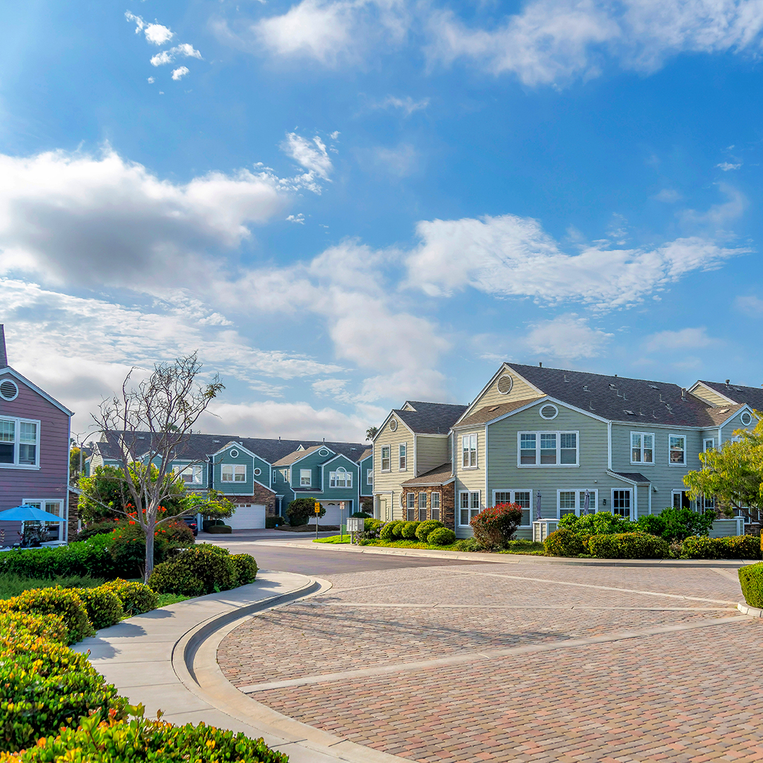 Residential area at Carlsbad, San Diego, California near the mountain. There is a pathway with bricks at the front of the houses and hill with houses on top on the right.